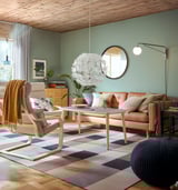 Modernes Wohnzimmer mit Ledersofa, Stuhl, Teppich, Spiegel, Lampe und grünen Wänden.