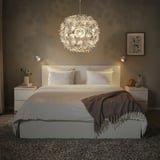 Modernes Schlafzimmer mit großer, kugelförmiger, weißer GRIMSÅS-Pendelleuchte mit Lichtmustern, weißem Bett, Nachttischen und grauer Decke.