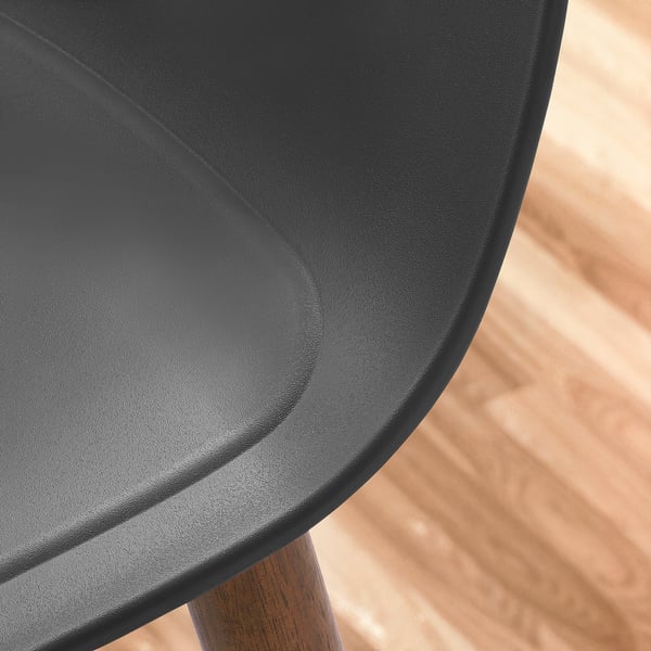 Nahaufnahme eines modernen, gebogenen, strukturierten schwarzen Sitzes auf Holzboden, der das glatte Finish und das robuste Design hervorhebt.