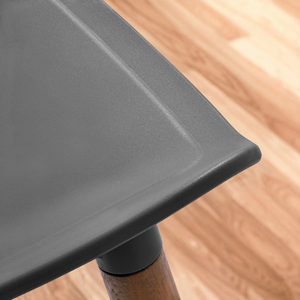 Schwarzer moderner Stuhl mit glatten, geschwungenen Kanten. Sitz aus geformtem Kunststoff, gestützt von stabilen Holzbeinen.