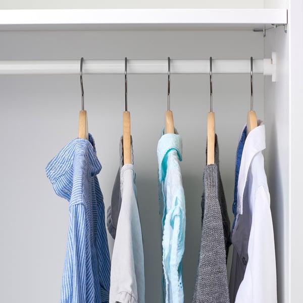 Schrank mit hölzernen Kleiderbügeln für Kinderkleidung, ordentlich organisiert auf einer Bar.