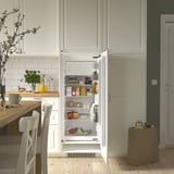 Offener weißer Kühlschrank in der Küche, in dem Speisen und Getränke auf verstellbaren Regalen ausgestellt werden.