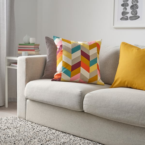 Chevron Kissen & gelbes Kissen auf grauer Couch, Bücher & Vase auf weißem Tisch.