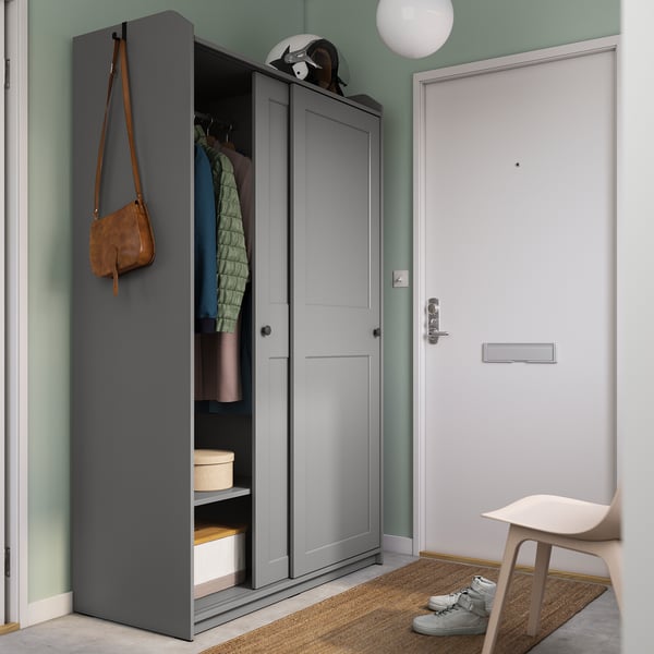 Moderner Eingangsbereich mit grauem HAUGA-Kleiderschrank, brauner Tasche, Turnschuhen und weißem Hocker auf einem Teppich.