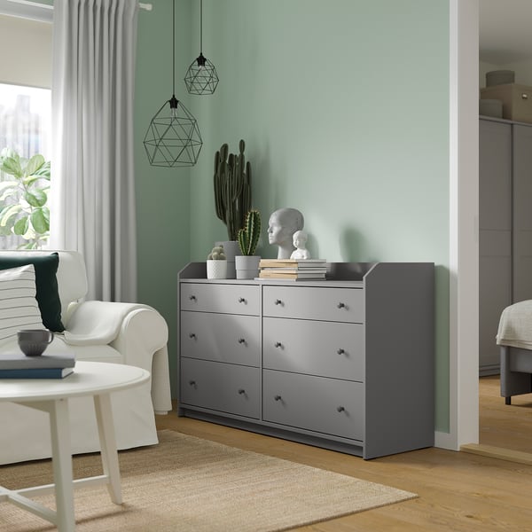 Modernes Zimmer mit HAUGA-Kommode, weißem Sofa, geometrischen Leuchten, grüner Wand.