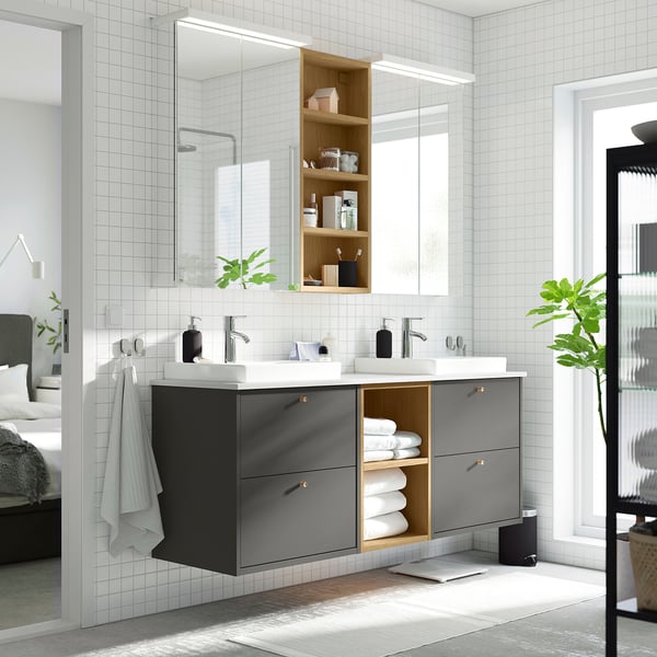 Modernes Badezimmer mit dunkelgrauem Doppelwaschtisch von HAVBÄCK, weißer Arbeitsplatte und großem Spiegel. Handtücher hingen neben dem offenen Regal.