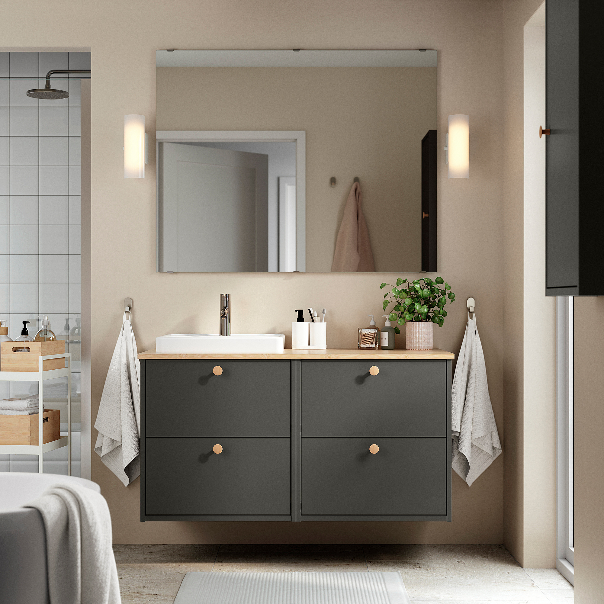 Modernes Badezimmer mit dunkelgrauem HAVBÄCK-Waschtisch, großem Spiegel, weißem Waschbecken und Wandhaken.