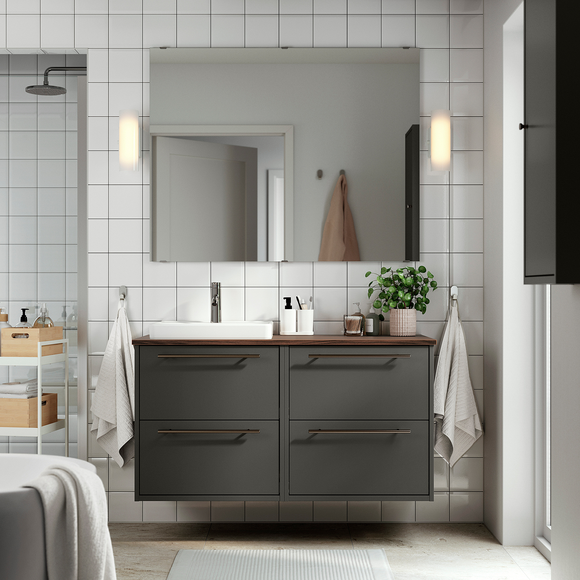 Modernes Badezimmer mit dunkelgrauem HAVBÄCK-Waschtisch, mehreren Schubladen, weißem Waschbecken, großem Spiegel und Wandhandtüchern.