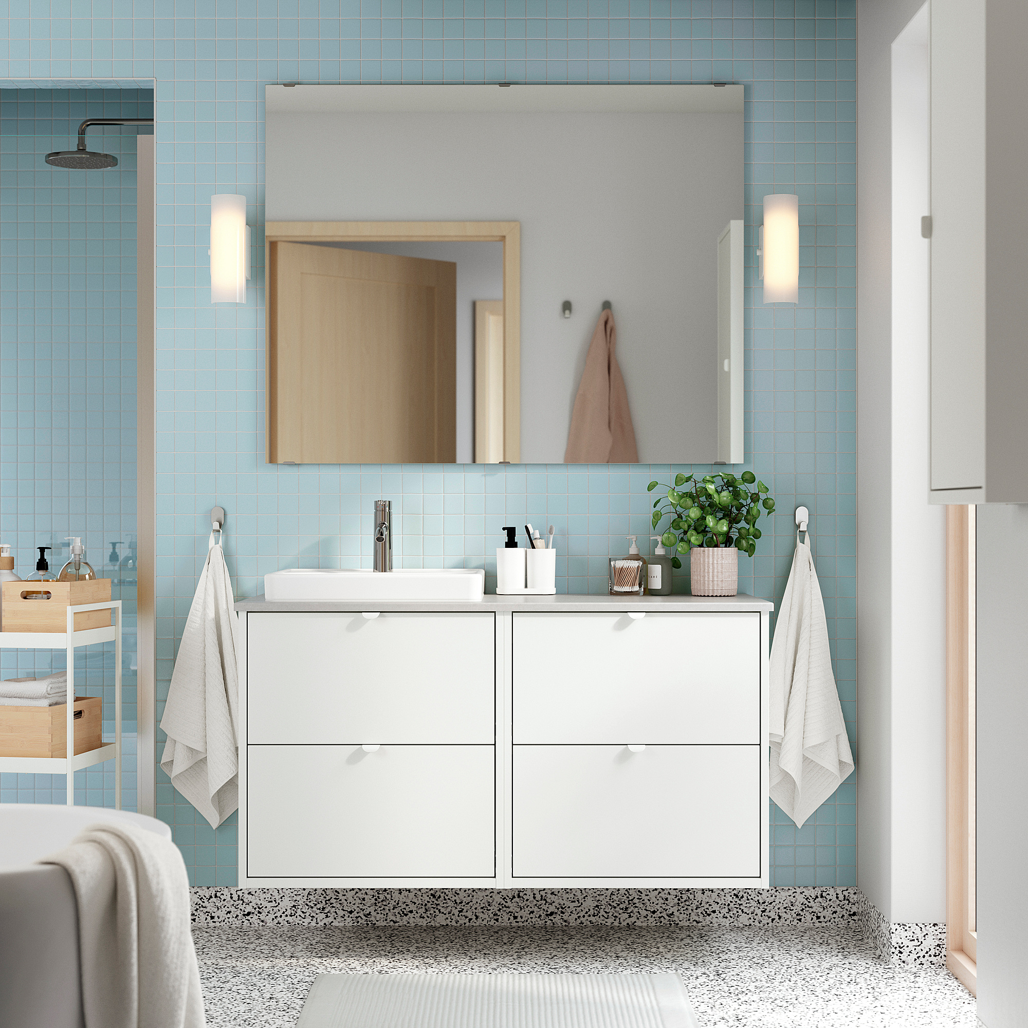 Modernes Badezimmer mit HAVBÄCK-Waschtisch, hellblauen Fliesen, Handtüchern, Pflanze, Spiegel, gemustertem Boden, Heizkörper.