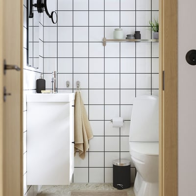 Modernes Badezimmer: weiß geflieste Wände, kompakter weißer Schrank, schwarze Akzente, elegante Keramik, minimalistische Einrichtung.