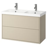 Ein cremefarbener Waschtisch mit zwei Waschbecken und zwei Schubladen. Der Waschtisch hat ein schlankes, modernes Design mit verchromten Armaturen und Knöpfen.