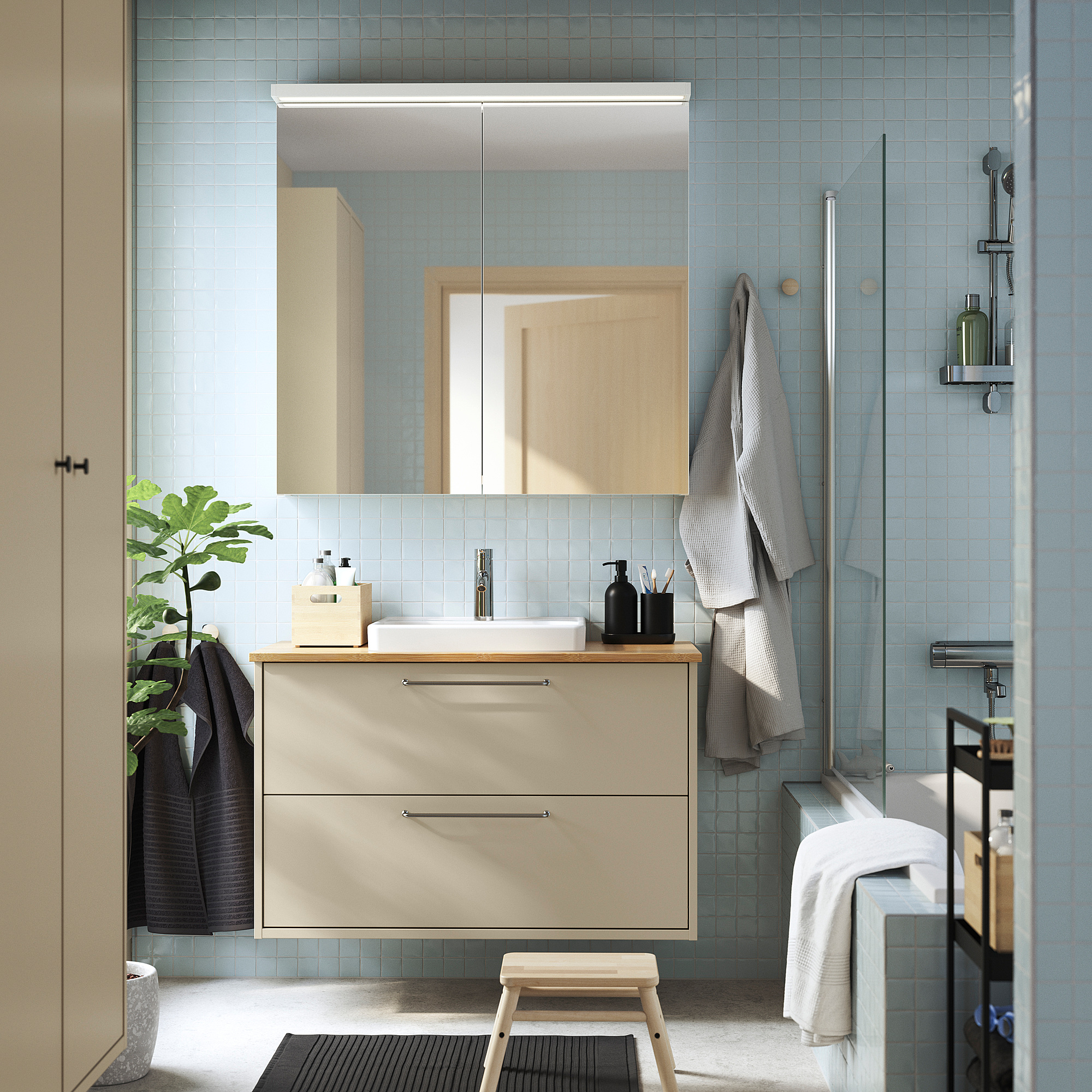 Modernes, minimalistisches Badezimmer mit hellblauen Fliesen. Beige HAVBÄCK Waschtisch, Waschbecken, Spiegel, Handtücher und Pflanze.