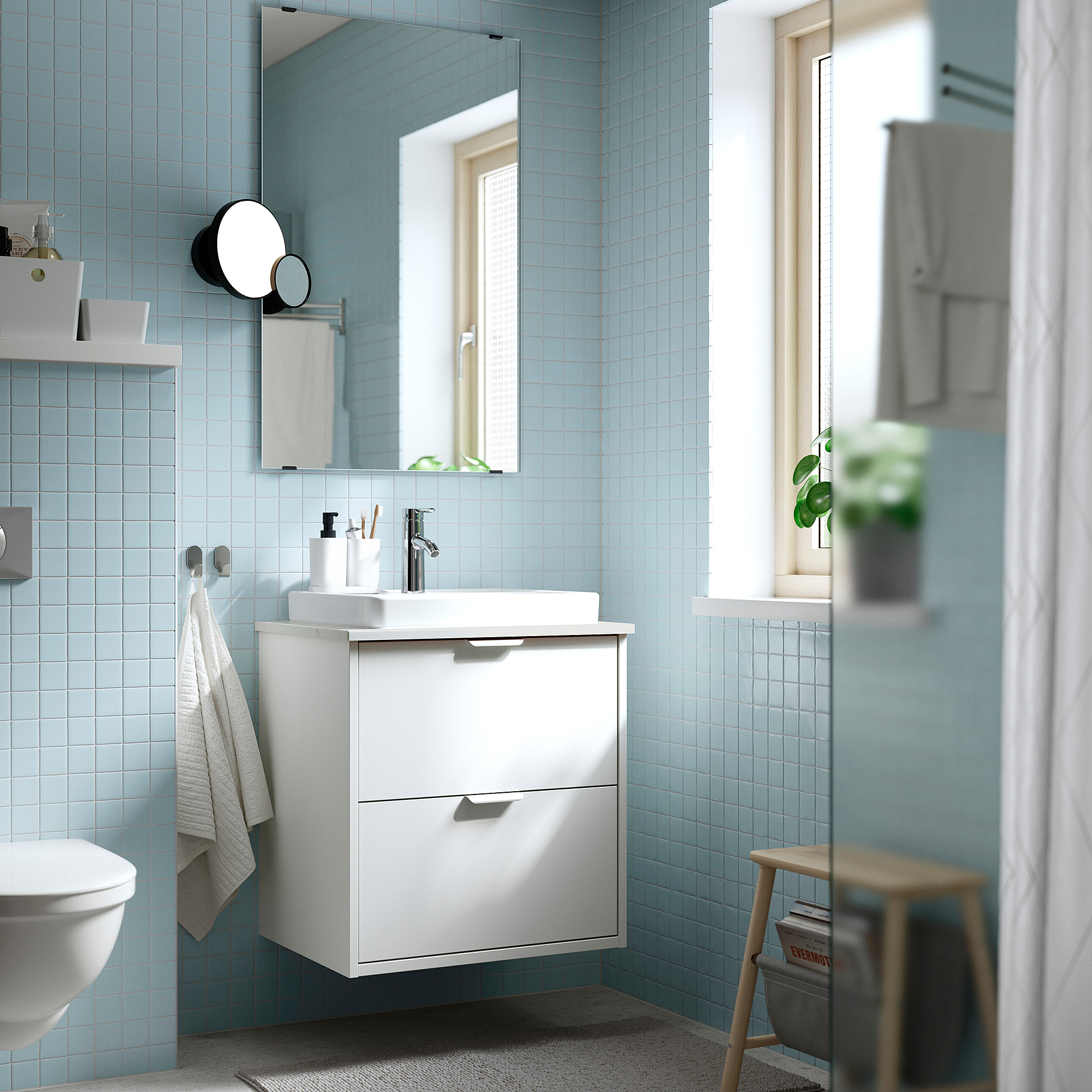 Hellblau gefliestes Badezimmer weißer HAVBÄCK-Waschtisch mit Waschbecken, Spiegel und Handtuchhaken; Modern und kompakt.