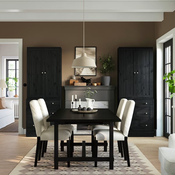 Modernes Esszimmer mit schwarzem HAVSTA-Tisch und Schränken, vier hellen Stühlen, symmetrischer Platzierung, weißer Pendelleuchte, gemustertem Teppich, minimalistisch.