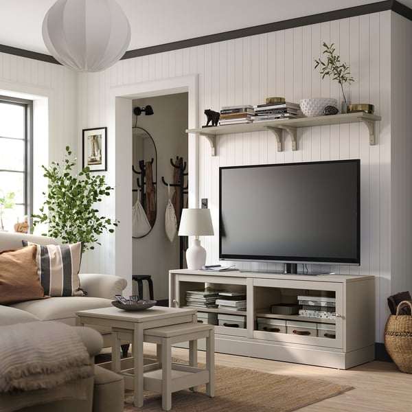 Modernes Wohnzimmer mit HAVSTA TV-Ständer, hellem Holz, offenen Regalen, Großbildfernseher, gemütlicher Couch, Beistelltisch, Stehleuchte und Topfpflanze.
