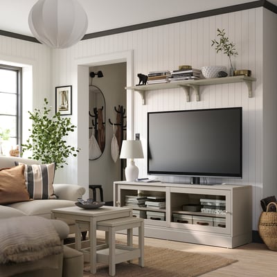 Modernes Wohnzimmer mit HAVSTA TV-Ständer, hellem Holz, offenen Regalen, Großbildfernseher, gemütlicher Couch, Beistelltisch, Stehleuchte und Topfpflanze.