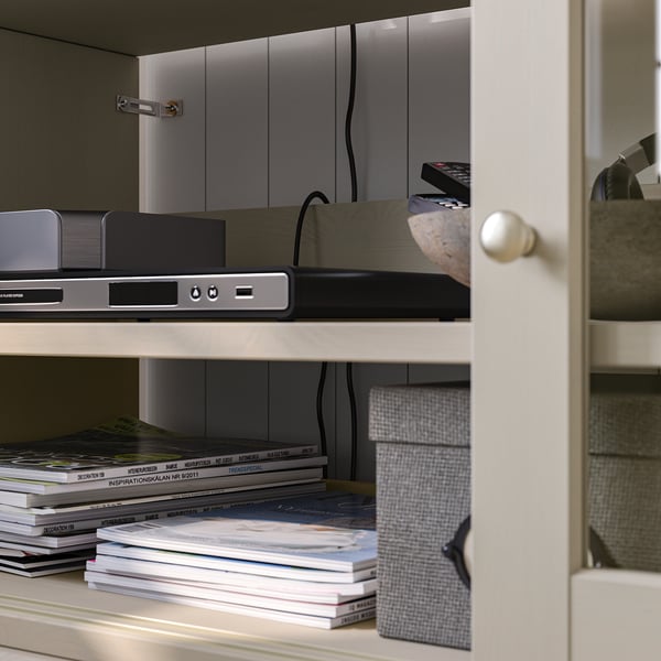 Weißes Holzregal mit Büchern, Elektronik und einer Fernbedienung.