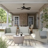 Moderne Terrasse mit HAVSTEN-Sofas, weiß, Mesh-Gewebe, niedriges Profil, unter gemauerter Veranda und Deckenventilator.