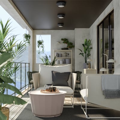 Moderne Außenterrasse mit weißem HAVSTEN-Sofa, rosa Tisch, Pflanzen und grauen Kissen.
