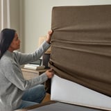 Person, die das weiche Kopfteil auf dem Schlafsofa einstellt, um die bequeme Unterstützung und den leicht zu reinigenden Bezug zu präsentieren.