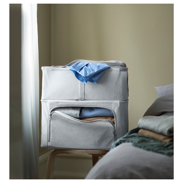 Aufbewahrungsbox aus grauem Stoff auf dem Stuhl. Hellblaues Tuch auf der Oberseite. Weich und stapelbar, ideal für die Garderobe.