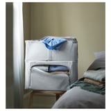 Aufbewahrungsbox aus grauem Stoff auf dem Stuhl. Hellblaues Tuch auf der Oberseite. Weich und stapelbar, ideal für die Garderobe.
