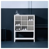 Weißes Schuhregal aus Holz, HEMNES, mit offenen Fächern, in dem fünf Paar Turnschuhe aufbewahrt werden, an einer blauen Wand.