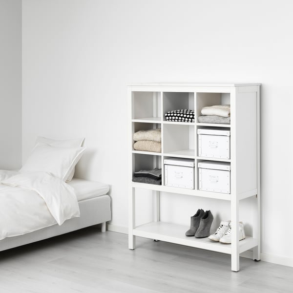 Weißer HEMNES Holzschrank, rechteckig, mit Regalen und gealterten Metallbehältern.
