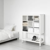 Weißer HEMNES Holzschrank, rechteckig, mit Regalen und gealterten Metallbehältern.
