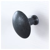 Haken aus schwarzem Metall; robuste, runde Ausführung; an einer schlichten Wand montiert.