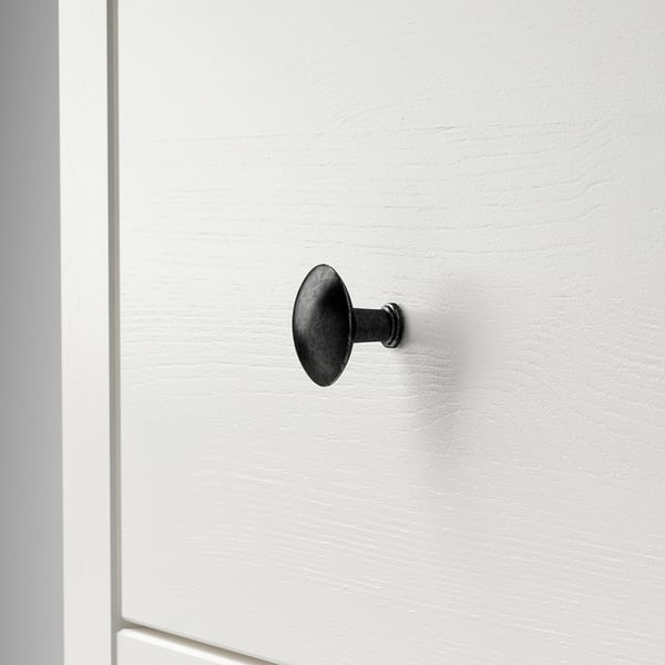 Einzelner dunkler Metallhaken, der an einer glatten weißen Tür montiert ist. Einfaches, robustes und schlankes Design.