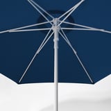 Blauer Sonnenschirm mit weißem Rahmen, teilweise offen gegen weiße Wand. Zeigt robustes Design und Belüftungsöffnung zur Reduzierung des Winddrucks.