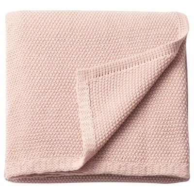 Hellrosa, weiche, gefaltete Decke. Hergestellt aus recyceltem Polyester. Gestrickte Struktur, rechteckig.