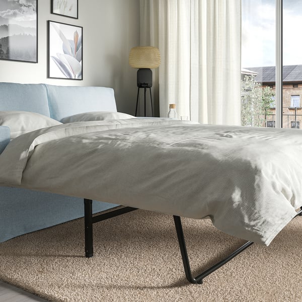 Bett in modernem Zimmer, ausziehbares Sofa mit Kissen, Stoffbezug, Metallbeine, in der Nähe des Fensters.