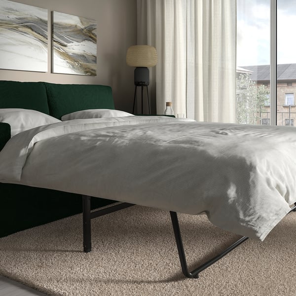 Modernes Schlafzimmer mit grauer Bettwäsche, grünem Kopfteil und Stehlampe. Fenster mit Blick auf die Stadt.