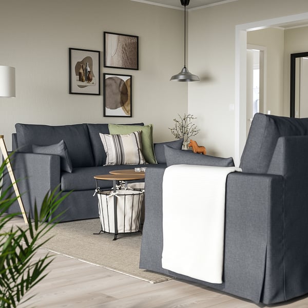 L-förmiges graues Sofa mit Kissen, Kissen und Couchtisch. Modernes Zimmer mit abstrakter Kunst und Licht.