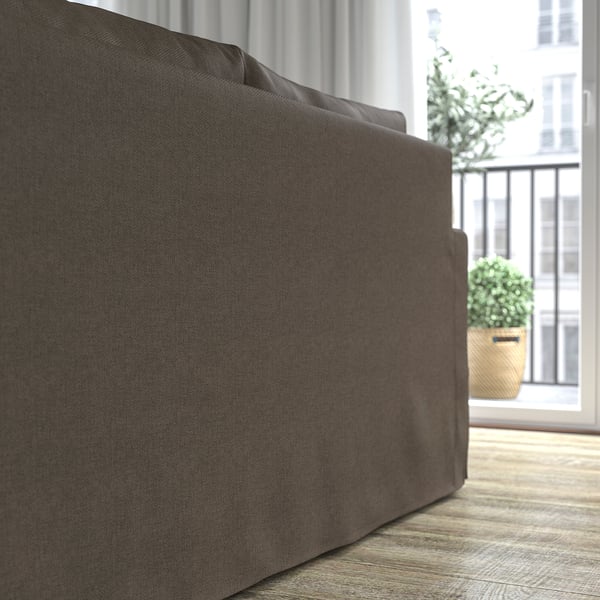 Ein großes, dunkles Sofa in der Nähe eines Balkons mit Topfpflanzen, das seine weichen Kissen und seinen einladenden Komfort zur Schau stellt.