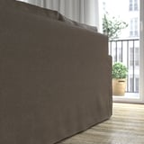 Ein großes, dunkles Sofa in der Nähe eines Balkons mit Topfpflanzen, das seine weichen Kissen und seinen einladenden Komfort zur Schau stellt.