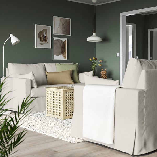 Wohnzimmer mit weißem HYLTARP-Sofa, moderner Einrichtung, dunkelgrüner Wand, abstrakter Kunst, weißen Möbeln.