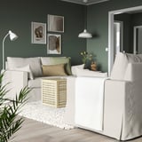 Wohnzimmer mit weißem HYLTARP-Sofa, moderner Einrichtung, dunkelgrüner Wand, abstrakter Kunst, weißen Möbeln.