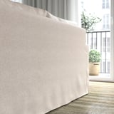 Ein beiges Sofa in der Nähe eines Fensters, mit Blick auf eine Balkonpflanze. Weiche Kissen mit hochelastischem Schaumstoff für mehr Komfort.