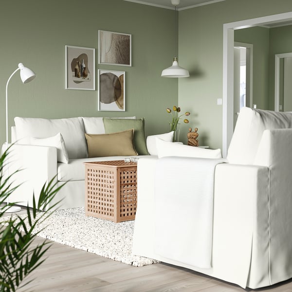 Gemütliches Wohnzimmer mit HYLTARP-Sofa, grünem Kissen, Beistelltisch und Kunst.