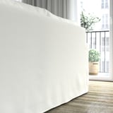 Ein weißes Sofa mit abnehmbarem, maschinenwaschbarem Bezug mit Blick auf ein Balkonfenster, das Komfort und einfache Reinigung bietet.
