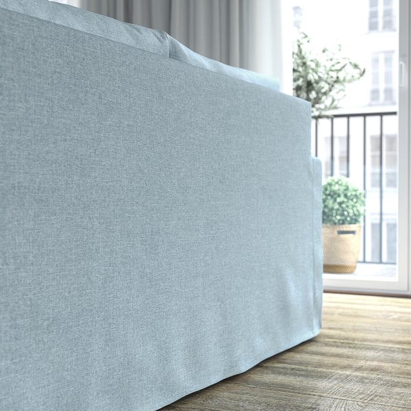Ein hellblaues Sofa in einem hellen Raum in der Nähe eines Fensters, das seine klaren Linien, weichen Kissen und einladenden Komfort zur Geltung bringt.