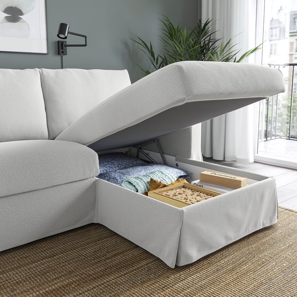 Weißes Sofa mit aufklappbarer Chaiselongue, der Stauraum mit Decken und Spielen freigibt.