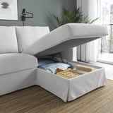 Weißes Sofa mit aufklappbarer Chaiselongue, der Stauraum mit Decken und Spielen freigibt.
