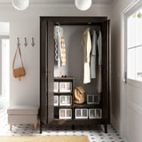 Brauner IDANÄS-Kleiderschrank mit Kleidung und Stauraum, Beleuchtung, Fliesenboden.