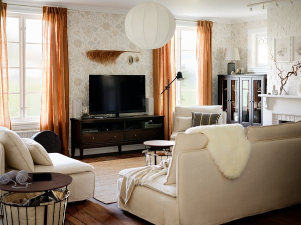 Gemütliches Wohnzimmer mit IDANÄS-TV-Bank in Braun, weichen Sofas, warmen Vorhängen und moderner Einrichtung.