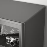 Schwarzer Glasschrank mit Schiebetüren, in dem eine Vintage-Kamera zu sehen ist.