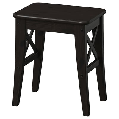 Ein dunkelbrauner INGOLF Holzhocker mit schlichtem, robustem Design und gekreuzten Beinen.